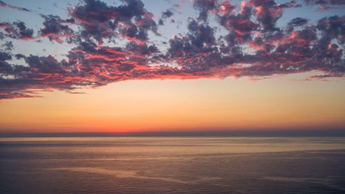 Free Stunning vibrant sunset with colorful clouds over calm ocean waters, perfect for travel themes. Stock Photo