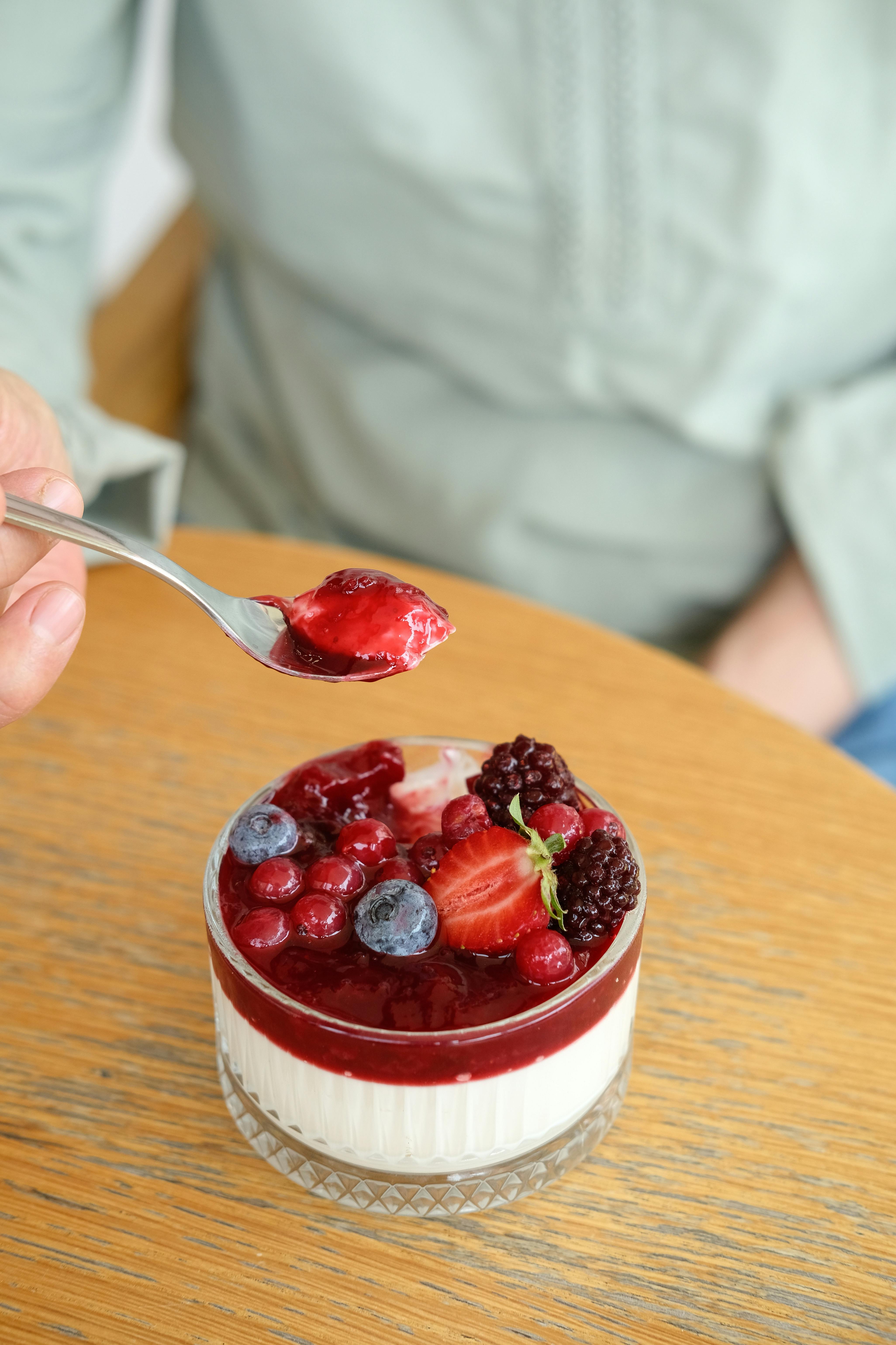 a person is spooning berries into a dessert