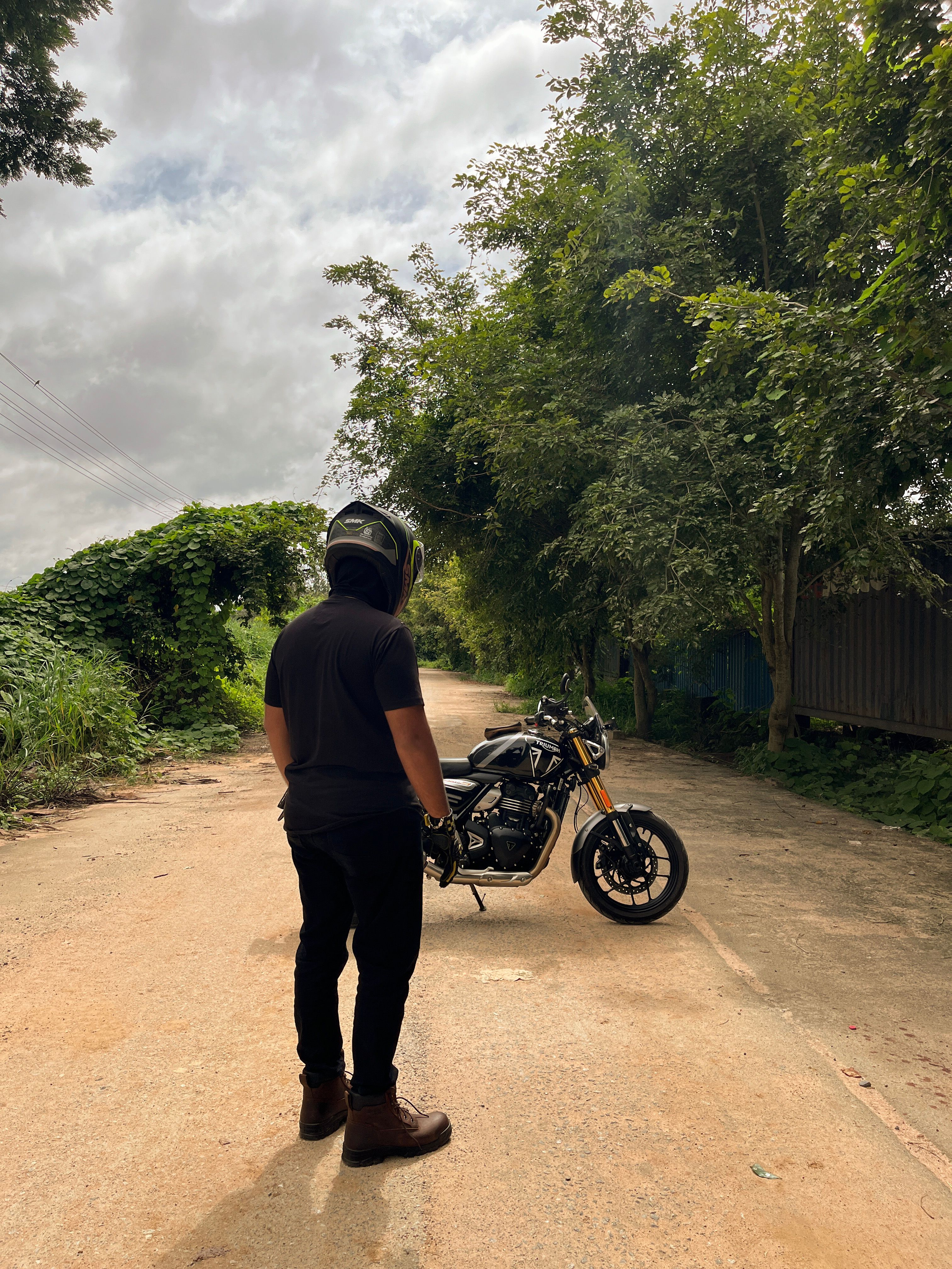 A man standing on the side of a road with a motorcycle · Free Stock Photo