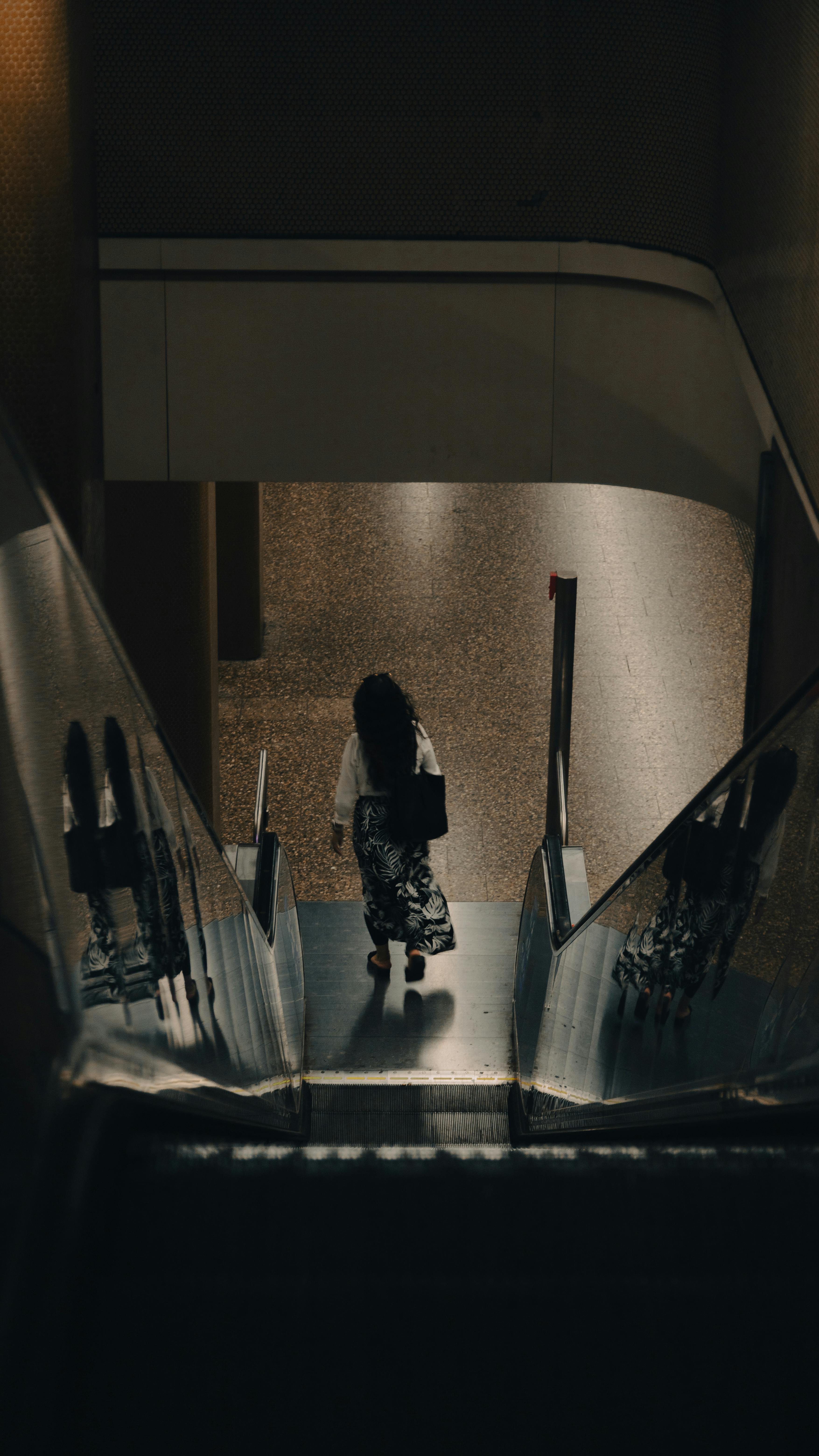 a woman walking down an escalator in a dark room