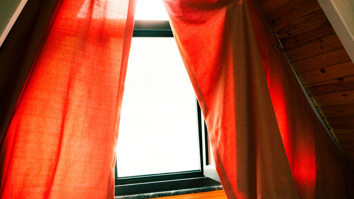 Photo: Zişan Özdemir / Pexels Warm sunlight through red curtains at an attic window