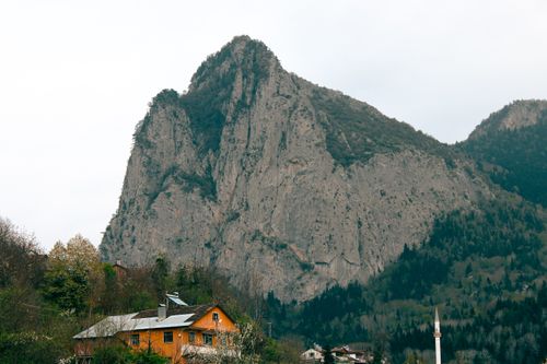Free Scenic view of houses nestled at the foot of a towering mountain in a tranquil spring landscape. Stock Photo