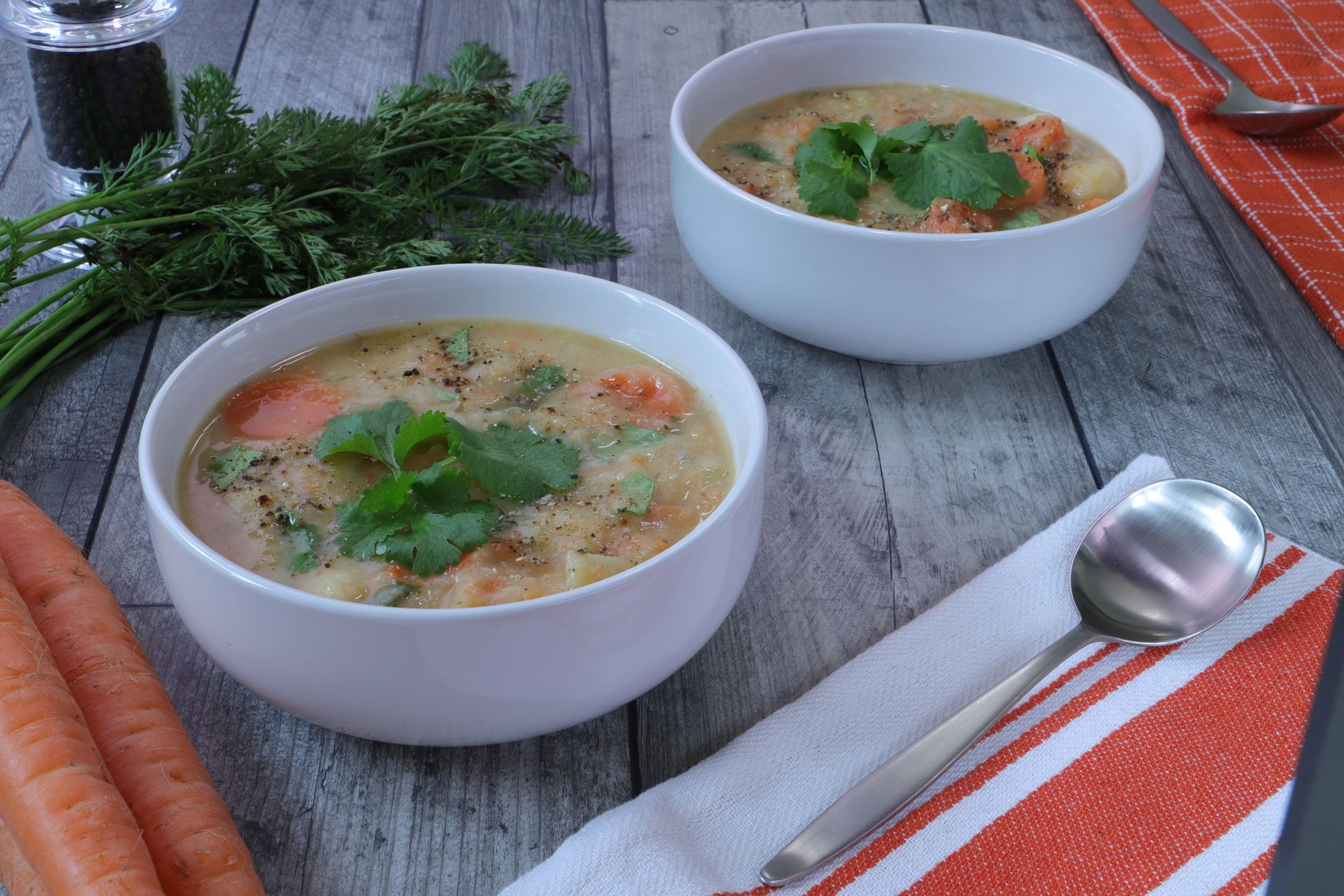 Bowl of chunky potato and carrot soup with fresh herb garnish