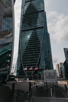 Contemporary glass skyscraper reflecting cityscape in an urban business district.