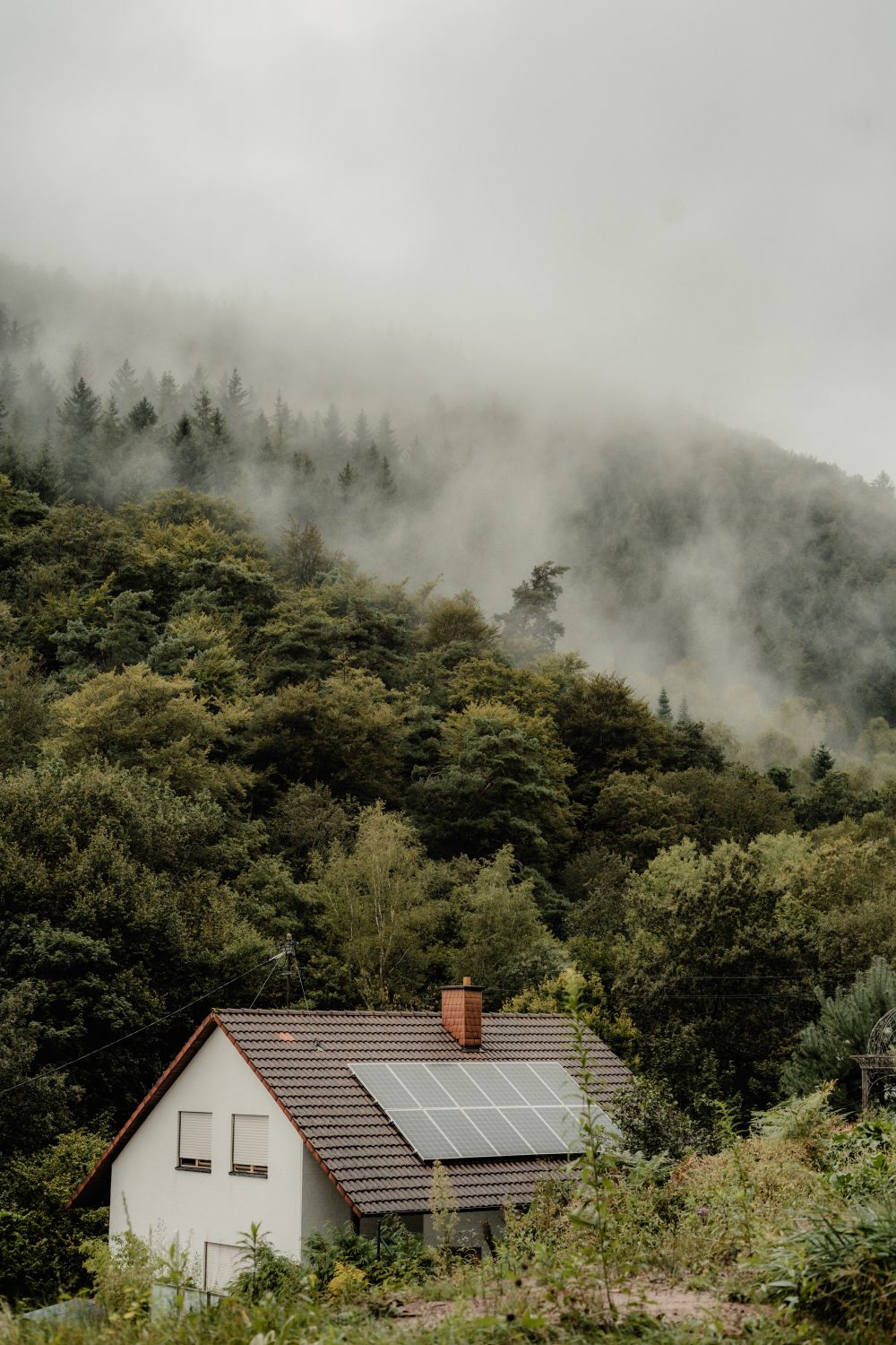 House with solar panels near a wooded hillside