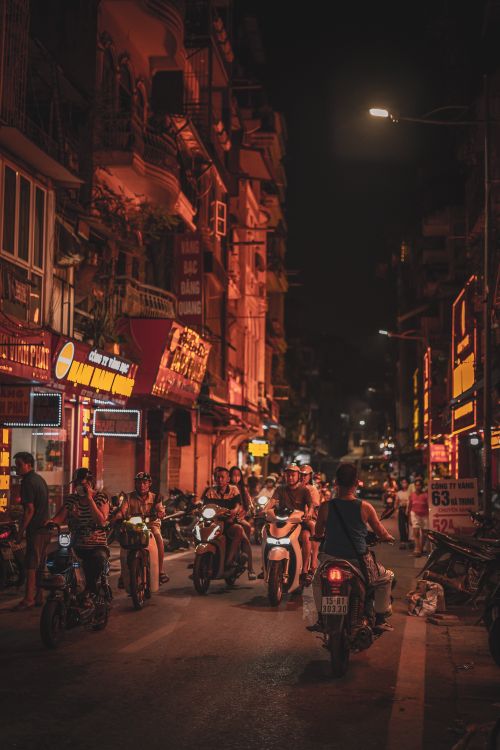 Free Nighttime city street scene filled with motorbikes under warm street lights. Stock Photo