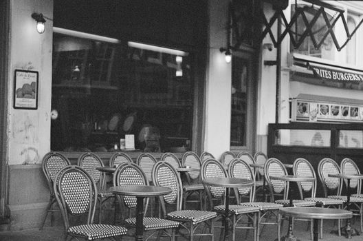 Empty bistro chairs and tables outside a café create a vintage ambiance.