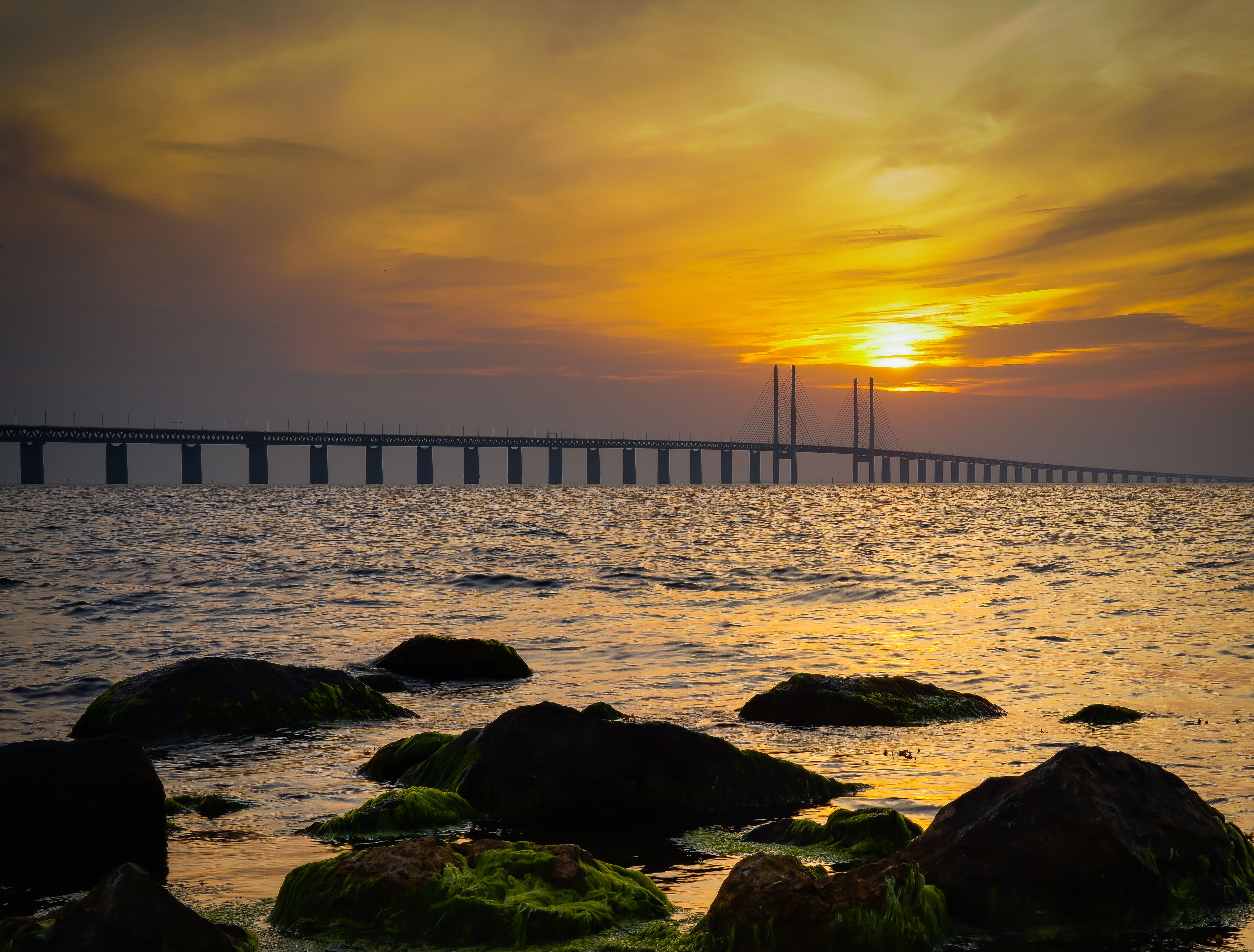 Stunning sunset view of the Öresund Bridge in Malmö, framing the serene seascape.