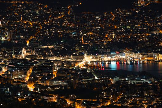 A breathtaking aerial view of a city lit up at night, reflecting in the water, capturing urban life.