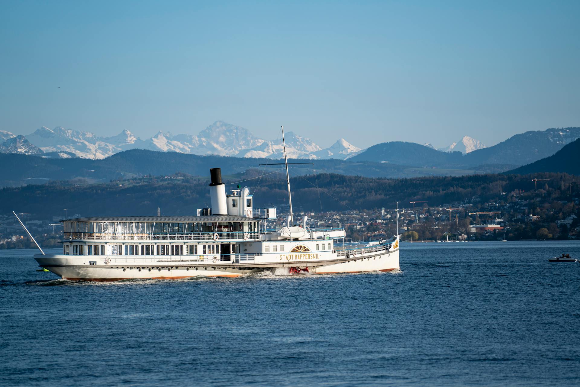 A beautiful steamboat cruises on a lake with mountains in the background, ideal for travel themes.