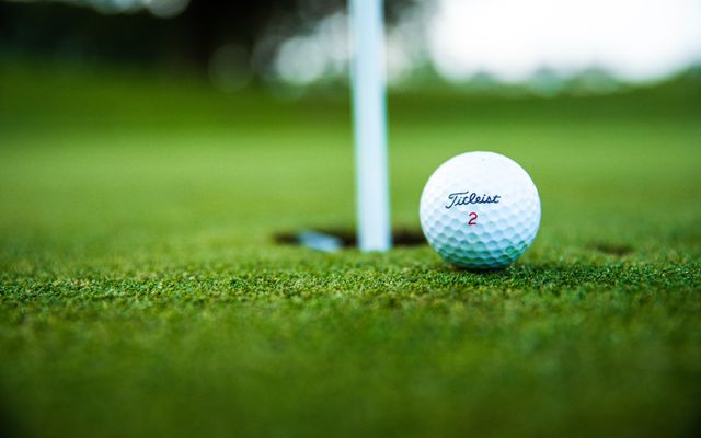 A Titleist golf ball on the green beside the hole