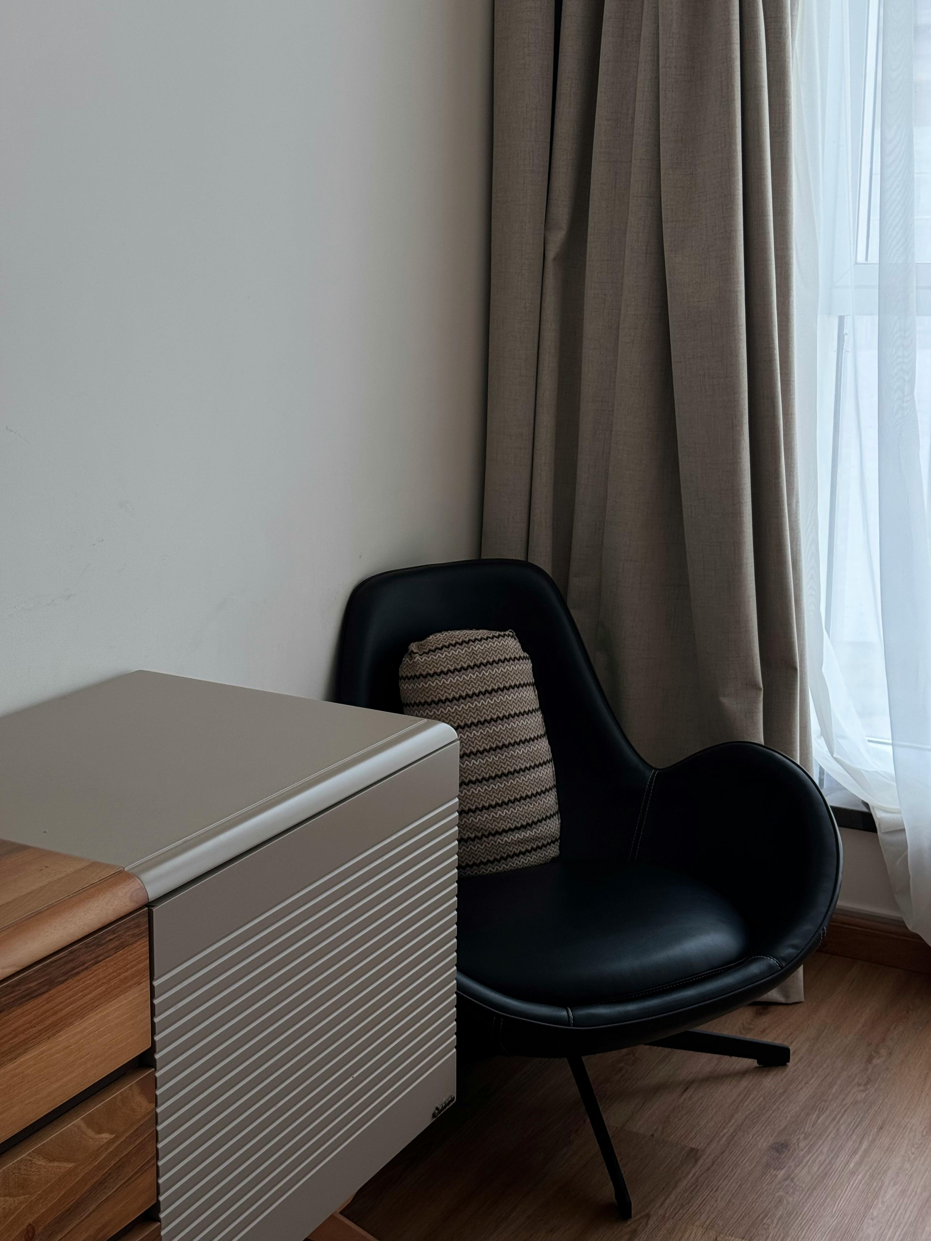 Free Stylish room corner with a black chair, warm lighting, and elegant curtains. Stock Photo