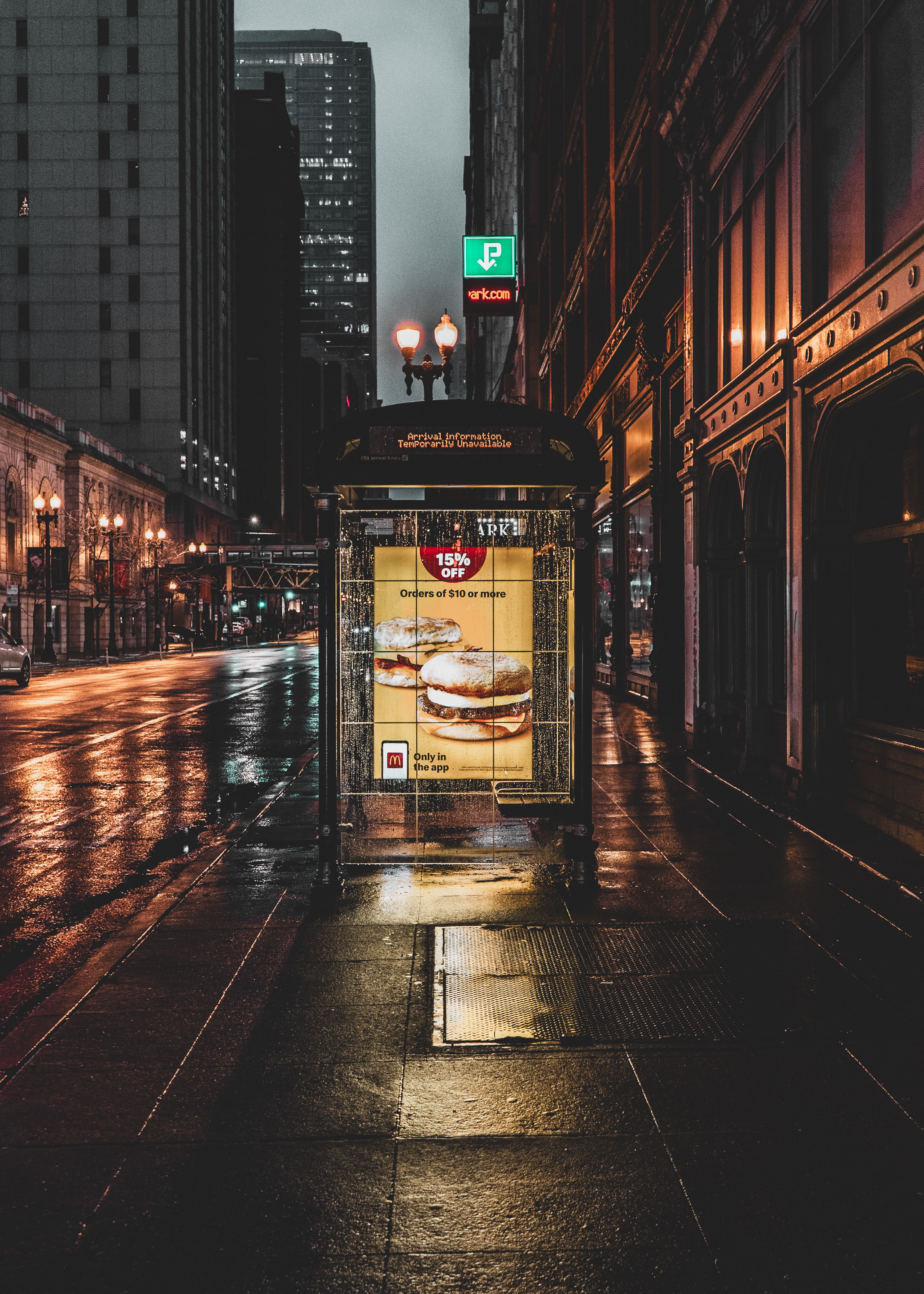 Nighttime urban scene on a rainy street in downtown Chicago with illuminated ads.
