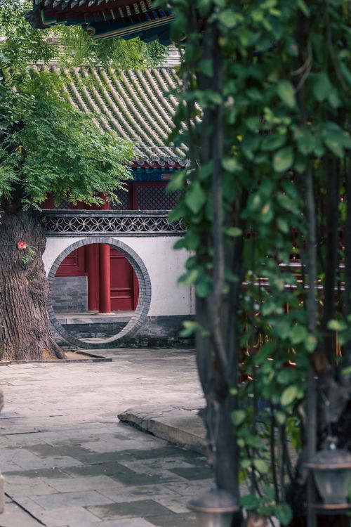 Free Serene view of a traditional Chinese garden with a circular moon gate and lush greenery. Stock Photo