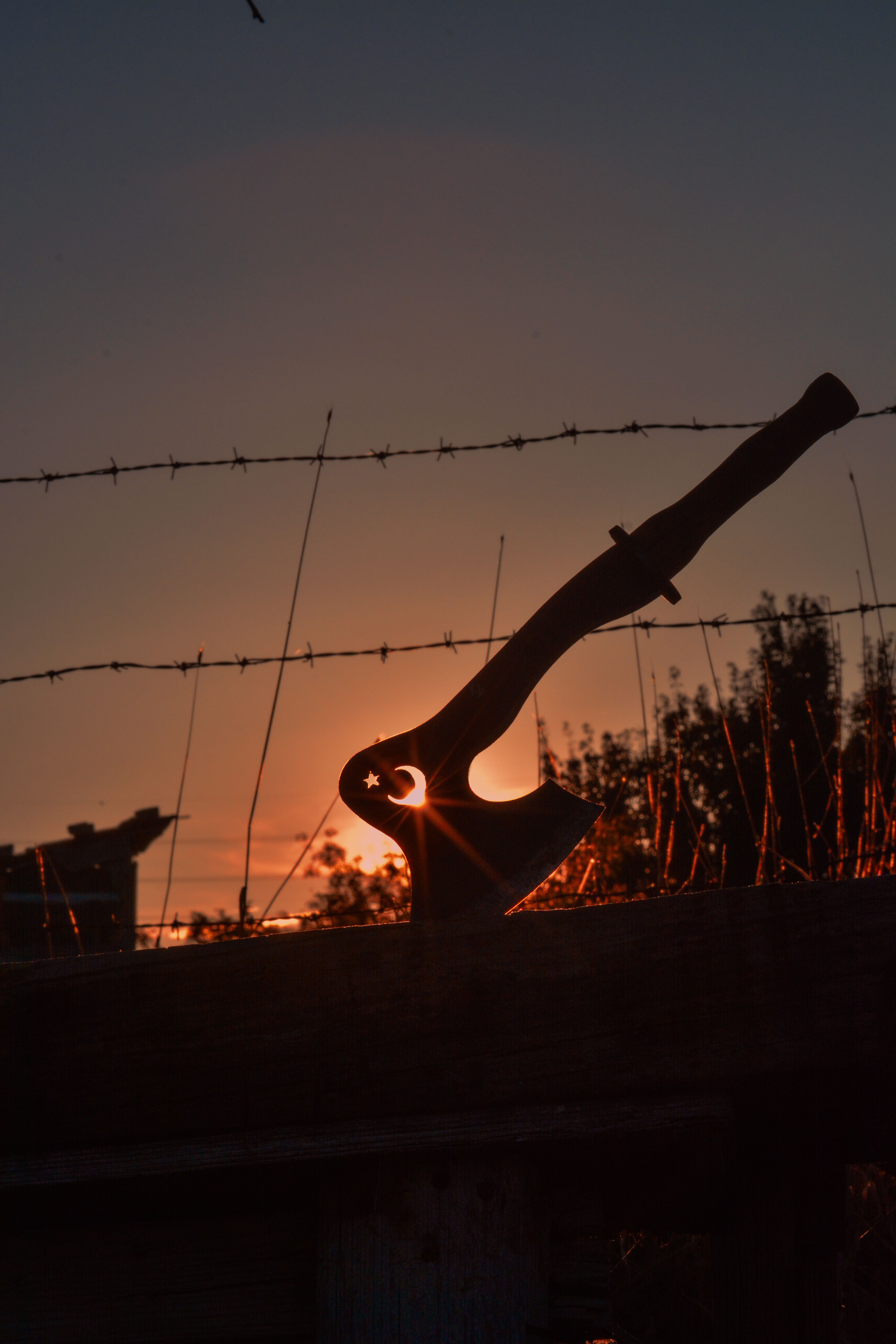 A striking silhouette of a Turkish axe with symbols set against a vivid sunset sky.