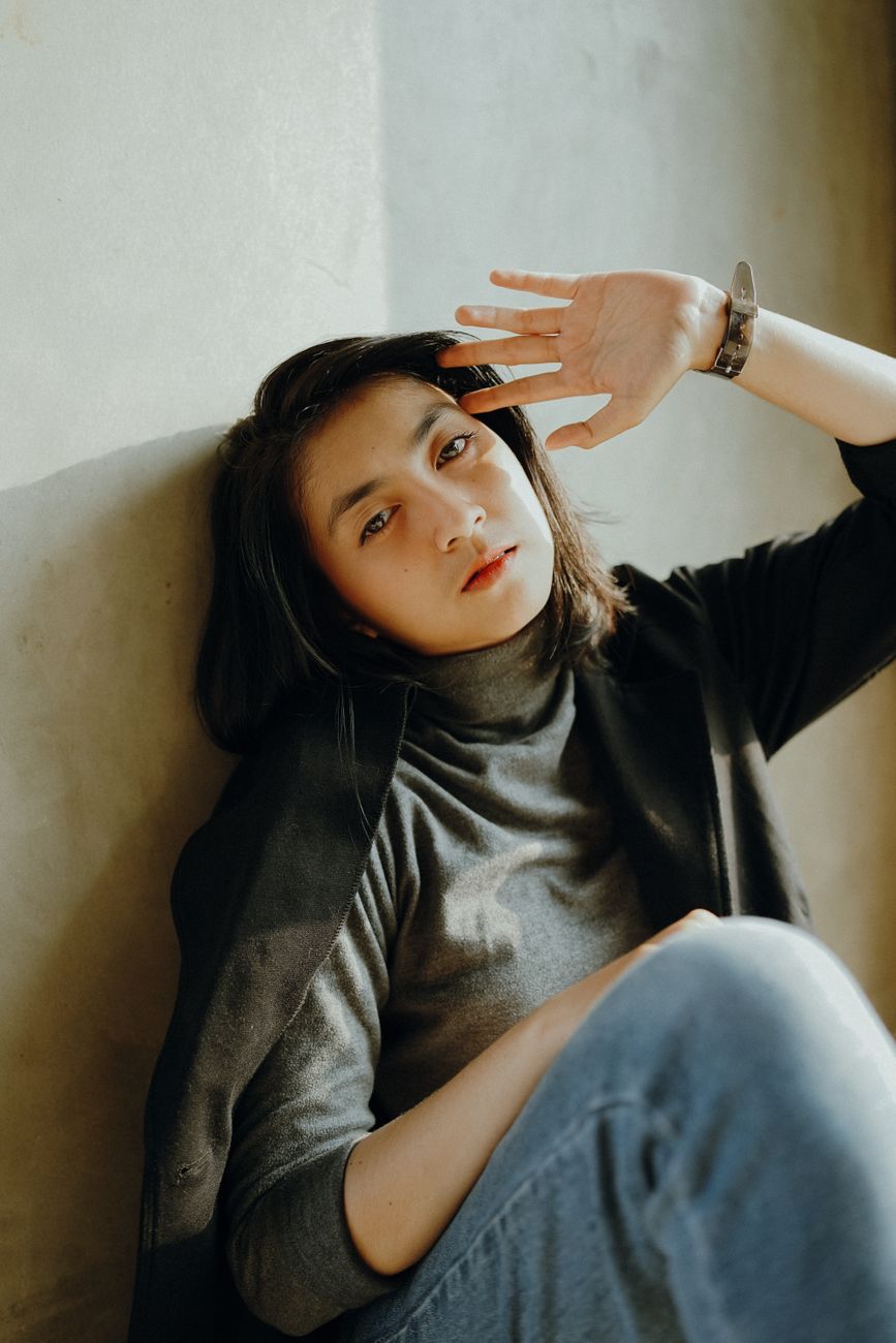 Elevated portrait of a fashionable woman posing indoors in natural light.