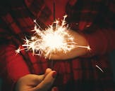 在黑暗背景下，一只手握着明亮的烟火，非常适合节日场合