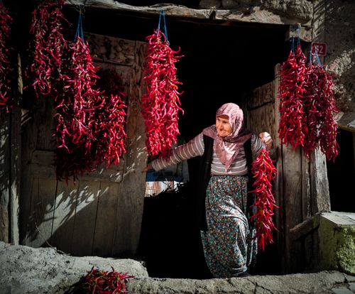 Free A woman selling red chili peppers in a traditional Turkish market adds vibrant color to the street scene. Stock Photo