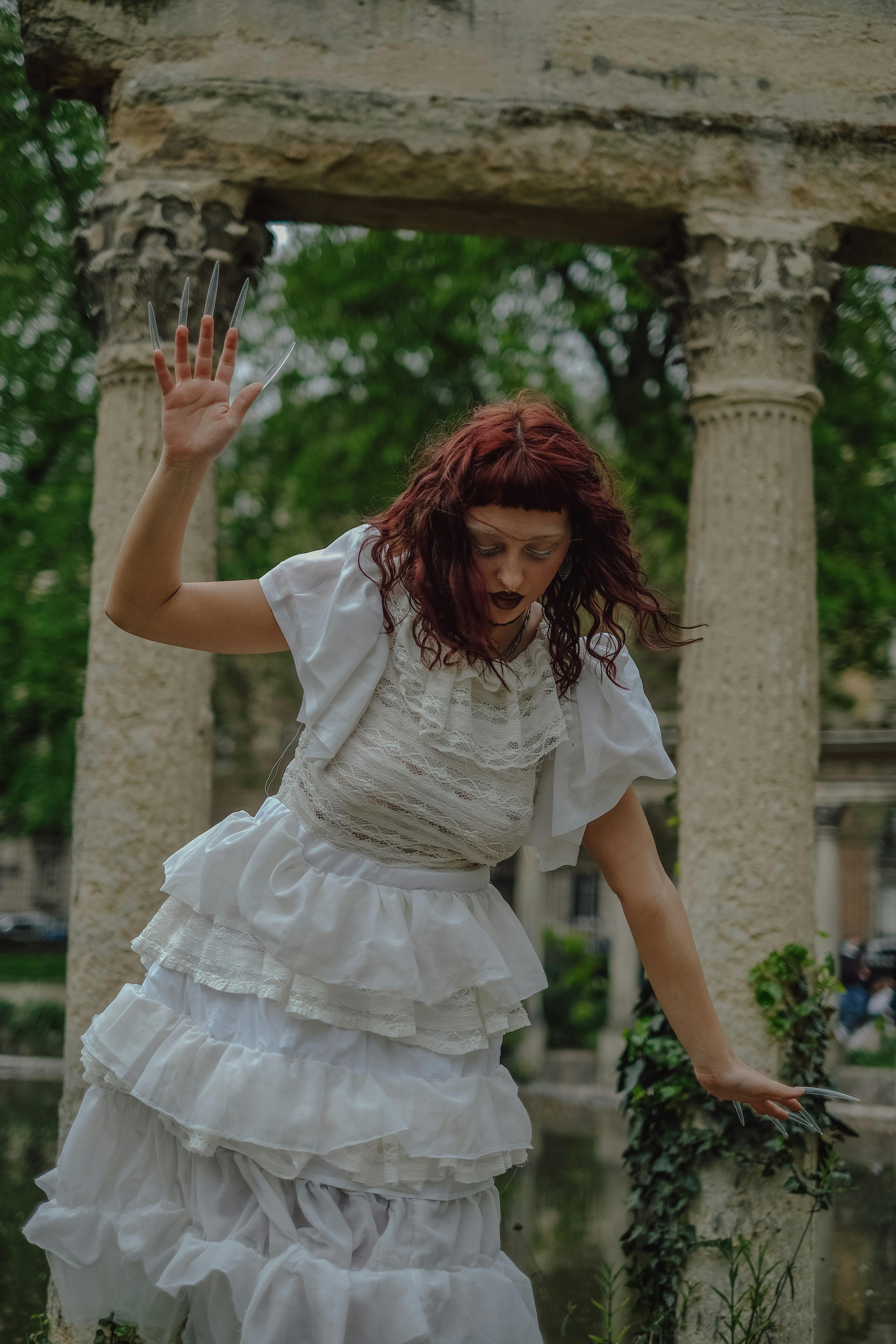 a woman in a white dress is standing in front of a fountain