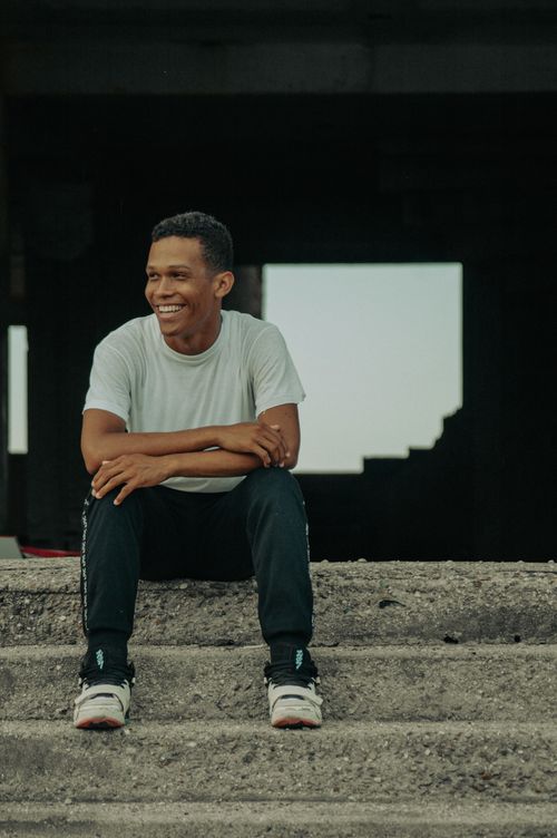 Free A cheerful adult man in casual wear sits on steps, exuding a relaxed and joyful vibe. Stock Photo