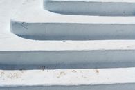 A close-up of textured white steps outdoors, showing winter wear in an urban setting.