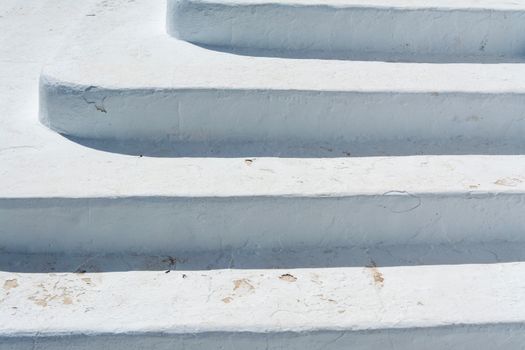 A close-up of textured white steps outdoors, showing winter wear in an urban setting.