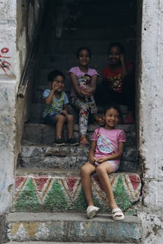 Happy children sitting on colorful stairs in Alexandria, Egypt, enjoying a playful moment.