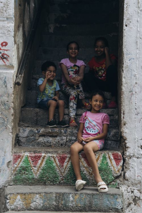 Free Happy children sitting on colorful stairs in Alexandria, Egypt, enjoying a playful moment. Stock Photo
