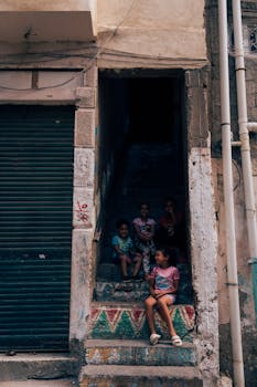 Four children sit on colorful painted steps in an urban area of Alexandria, Egypt.