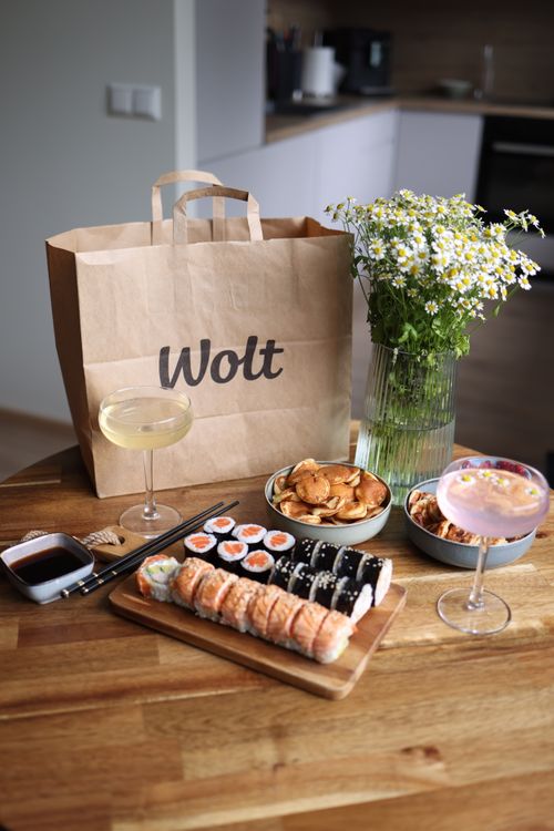 Free Indoor setting featuring sushi, cocktails, and vibrant flowers for a cozy dining experience. Stock Photo