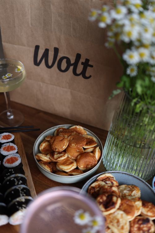 Free Delicious spread with sushi, mini pancakes, and flowers, creating a cozy dining atmosphere. Stock Photo