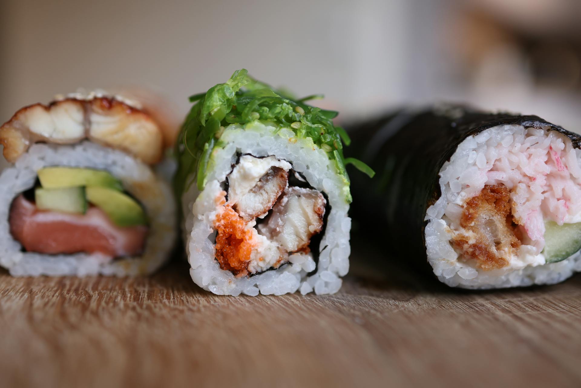 Close-up of assorted sushi rolls with various fillings on a wooden table.