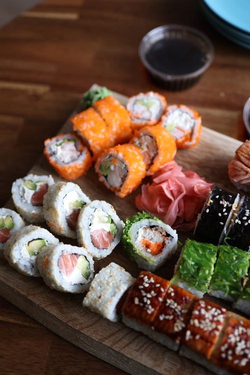 Free Delicious sushi assortment with salmon, avocado, and more on a wooden board. Stock Photo