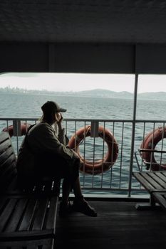 Person enjoying a quiet ferry ride with a city skyline visible across the water.