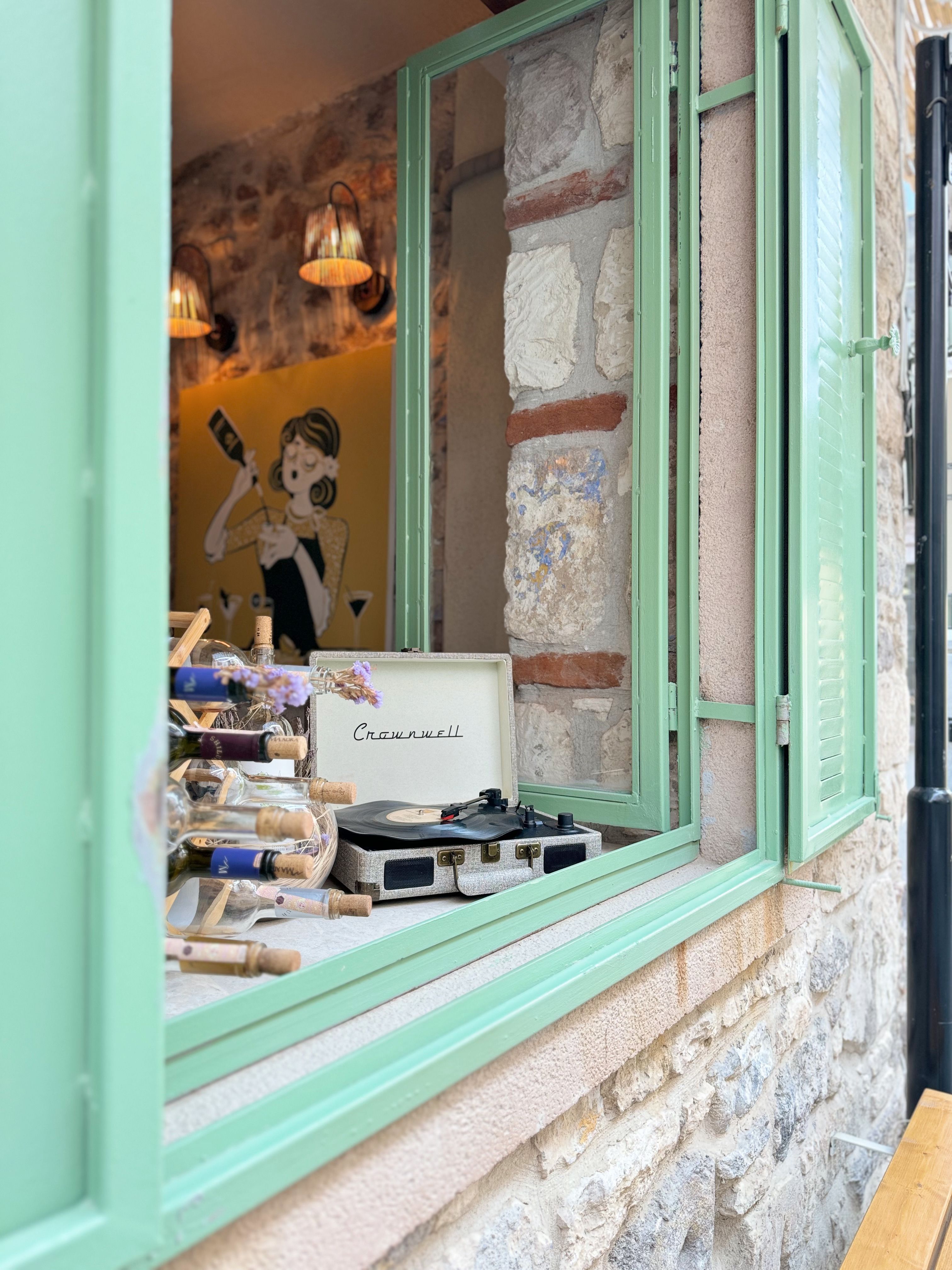 Charming window scene in Küçükköy, Türkiye with vintage decor and stone wall.