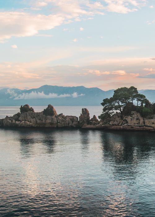 Free Serene Croatian coastline with rocky islands and soft twilight reflections. Stock Photo