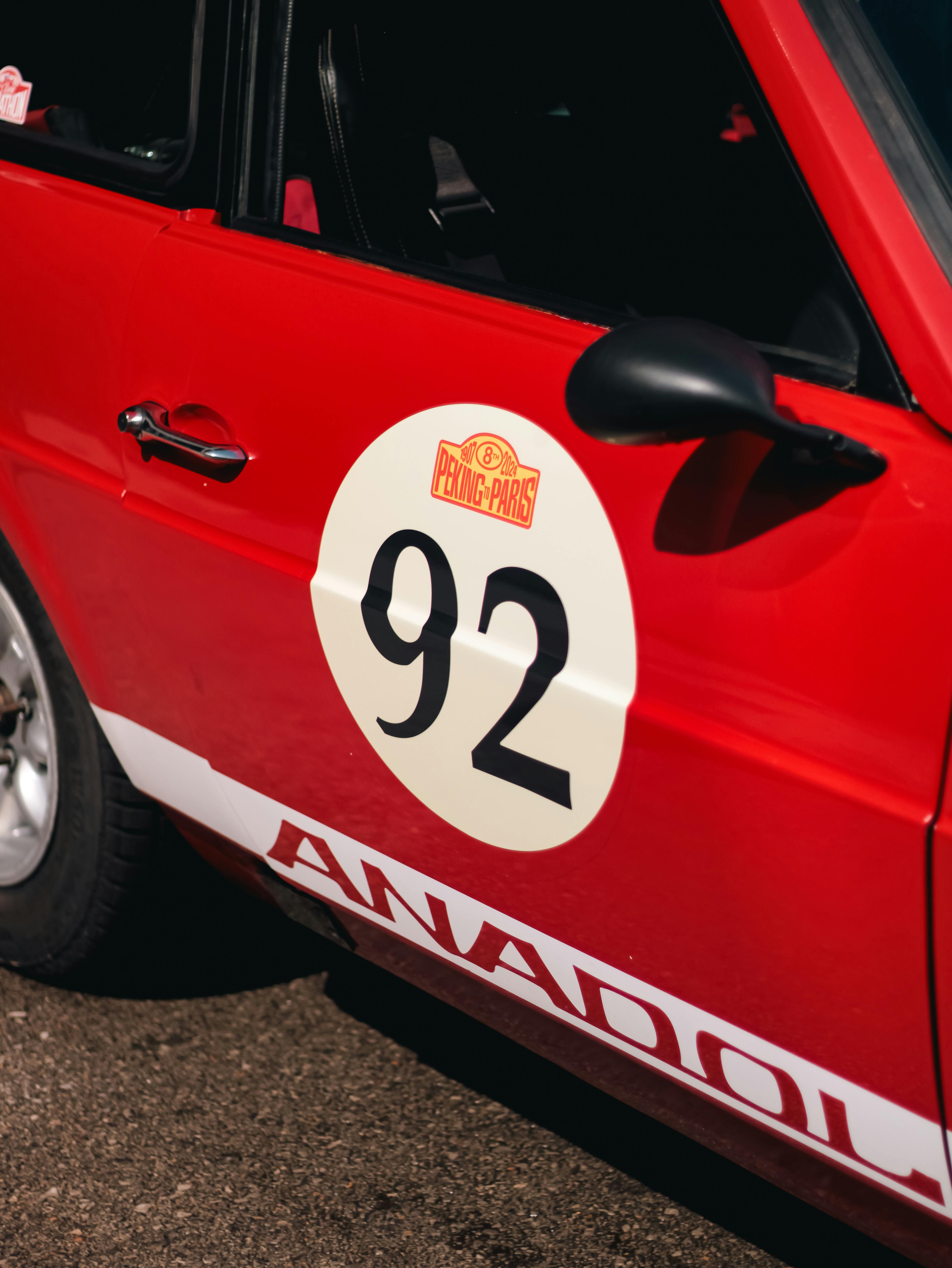 A red and white rally car with the number 92 on it · Free Stock Photo