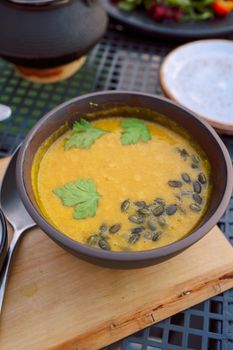 Savor the rich flavors of homemade pumpkin soup garnished with fresh parsley and pumpkin seeds.