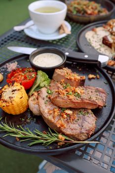 Delicious grilled steak dinner plate with vegetables, served outdoors on a sunny day.