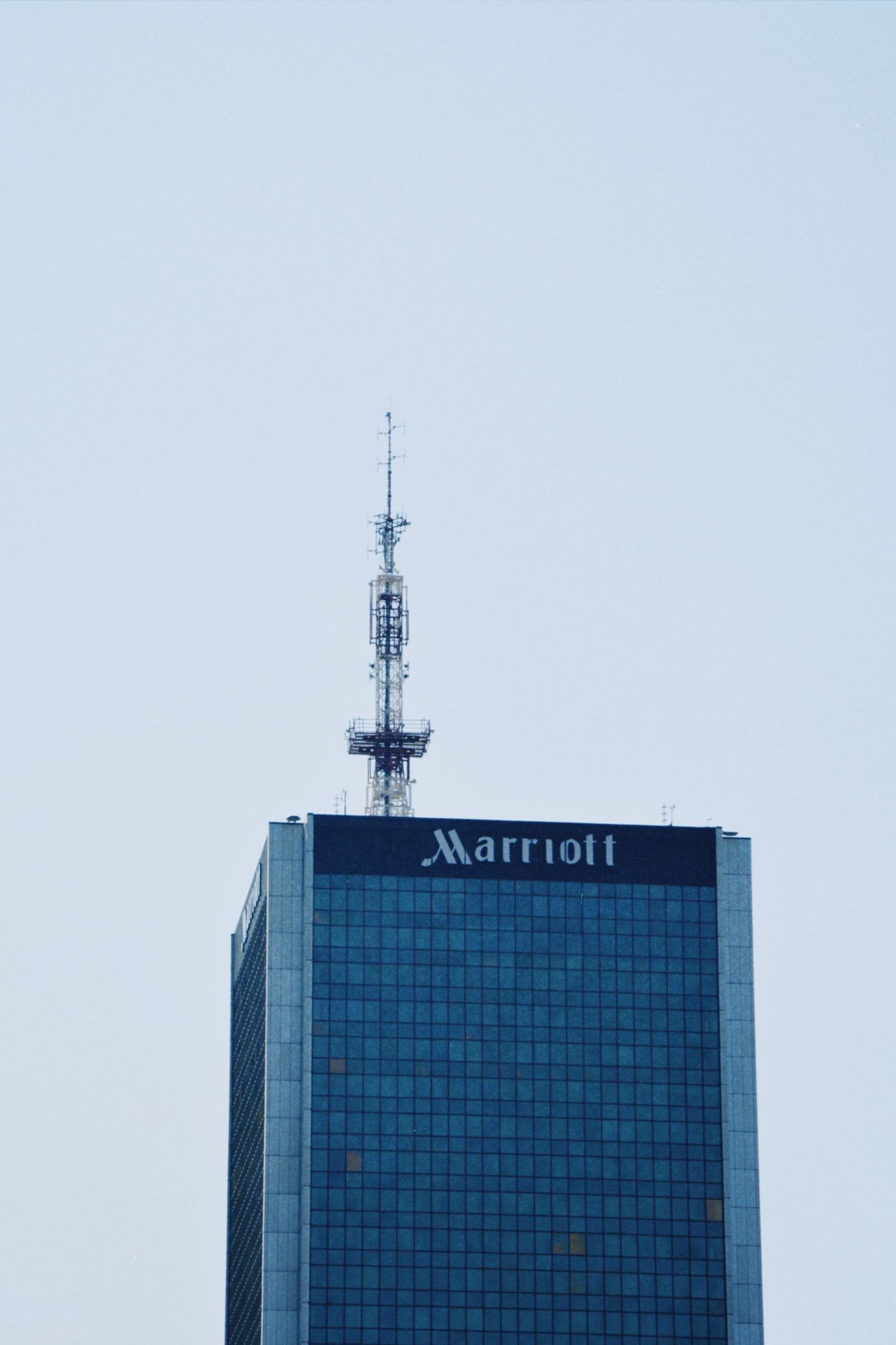 The top of the Warsaw Marriott Hotel tower against a clear blue sky in Warsaw, Poland