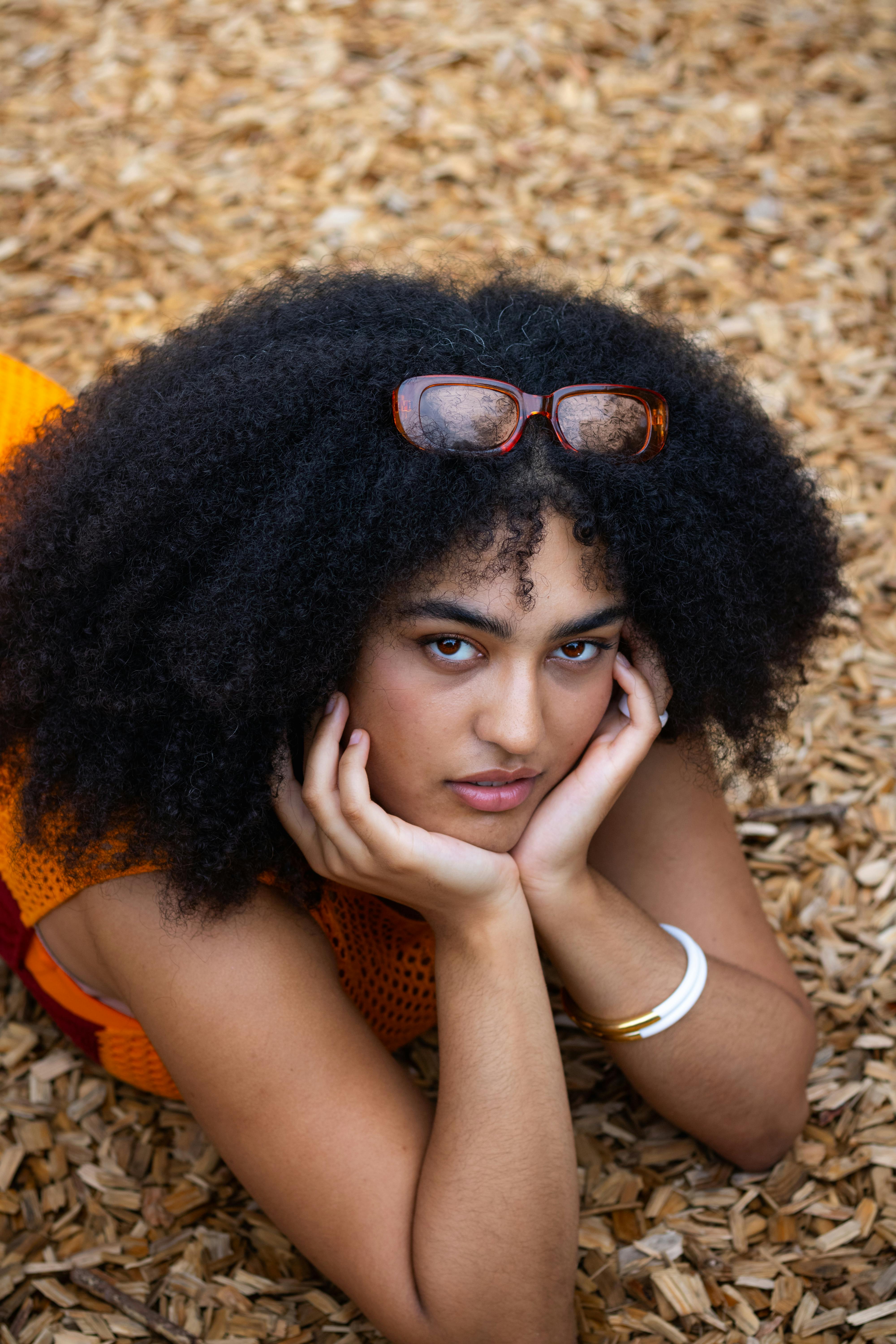 a woman with an afro wearing sunglasses laying on the ground