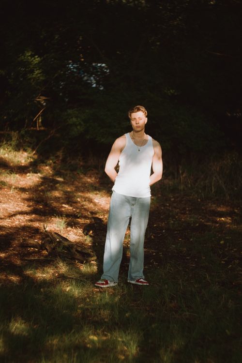 Free Young man in casual attire enjoying a sunny day outdoors, surrounded by nature. Stock Photo