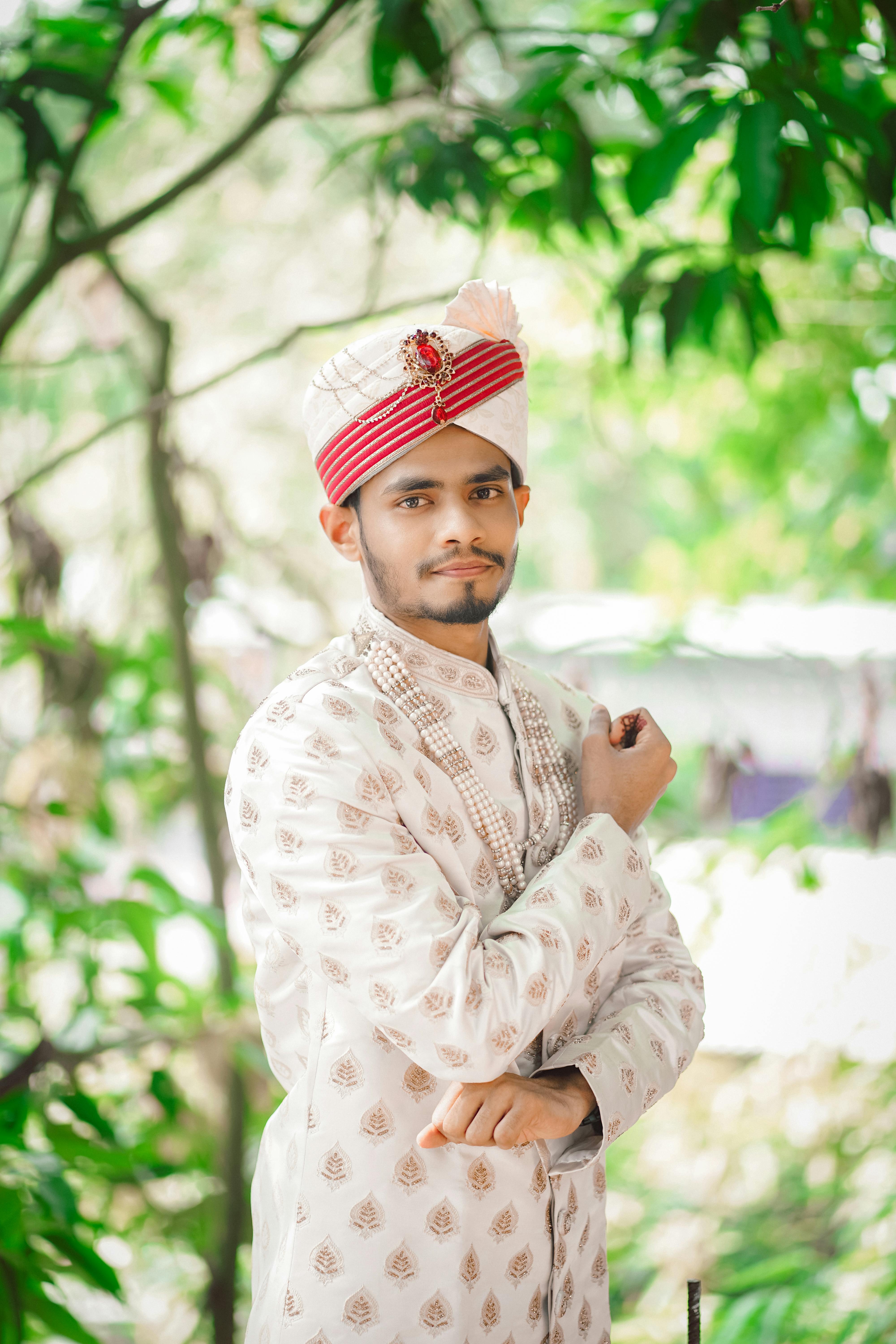 a man in a traditional indian outfit poses for a photo