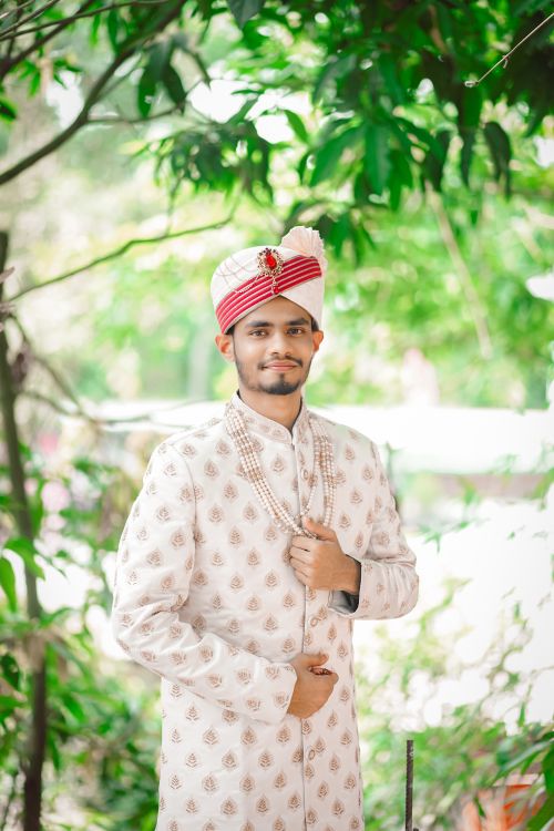 Free Young South Asian groom in traditional wedding attire amidst lush greenery. Stock Photo