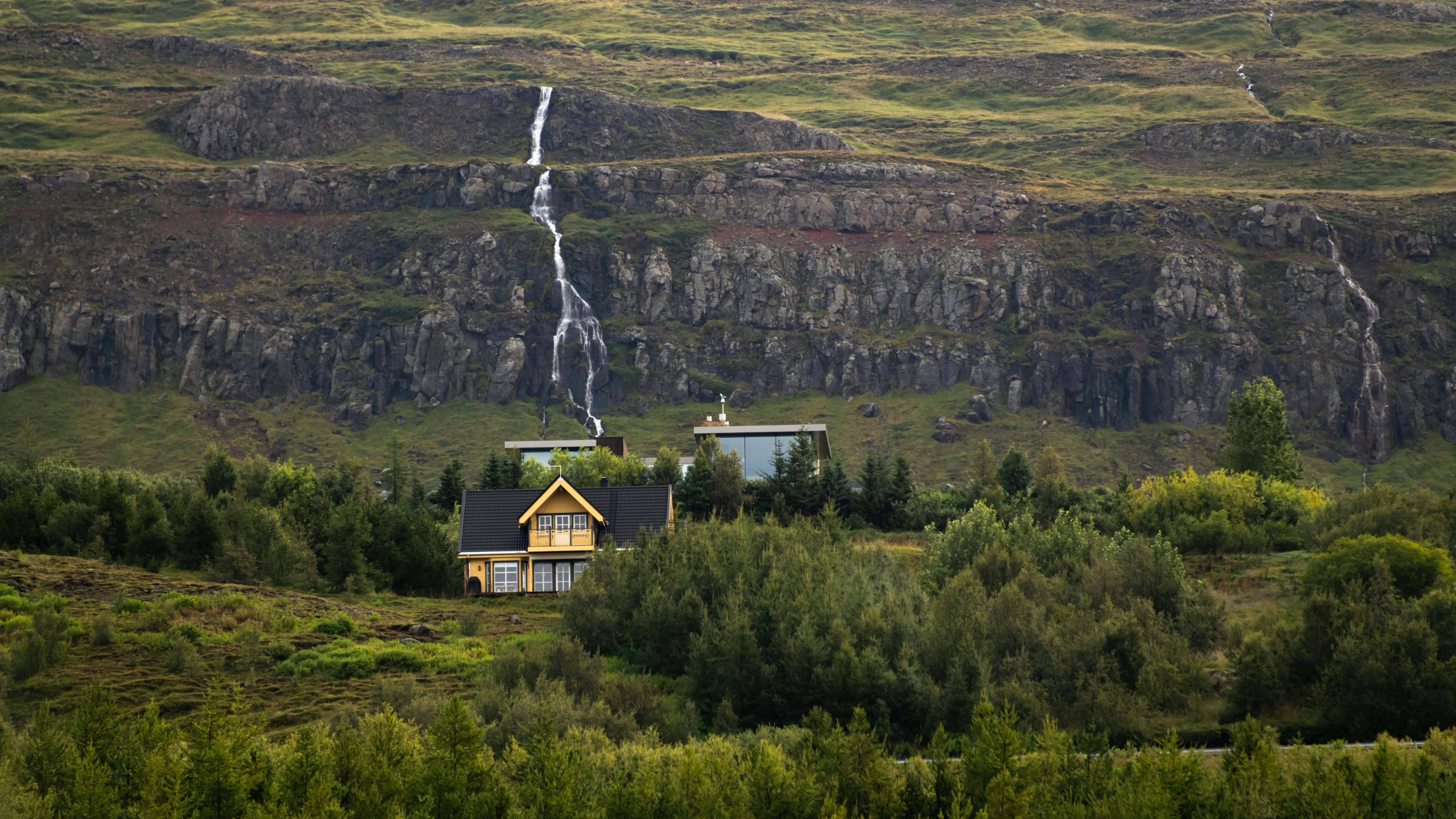 迷人的乡村房屋坐落在郁郁葱葱的绿色岩石瀑布之间