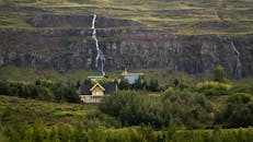 迷人的乡村房屋坐落在郁郁葱葱的绿色岩石瀑布之间