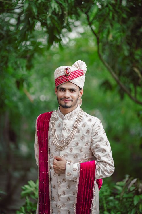 Free Bengali groom in elegant traditional attire, posing outdoors in greenery. Stock Photo