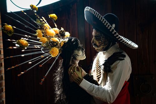Free Traditional Day of the Dead costumes with elegant face paint and floral decorations captured indoors. Stock Photo