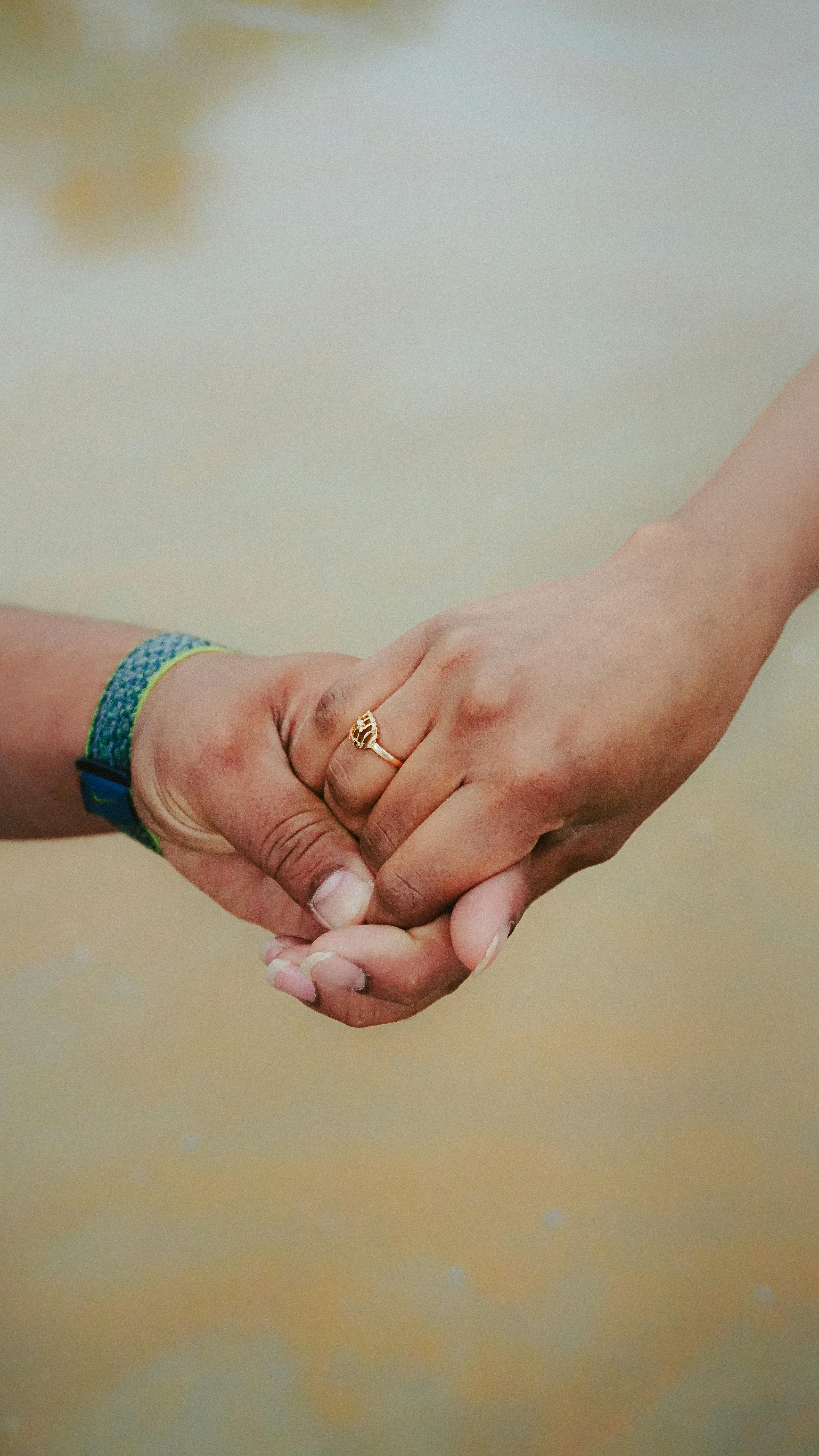 Free Intimate close-up of a couple's hands intertwined, symbolizing love and togetherness. Stock Photo