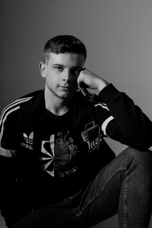 Free Black and white portrait of a man in a casual jacket and jeans, seated and pensive. Stock Photo